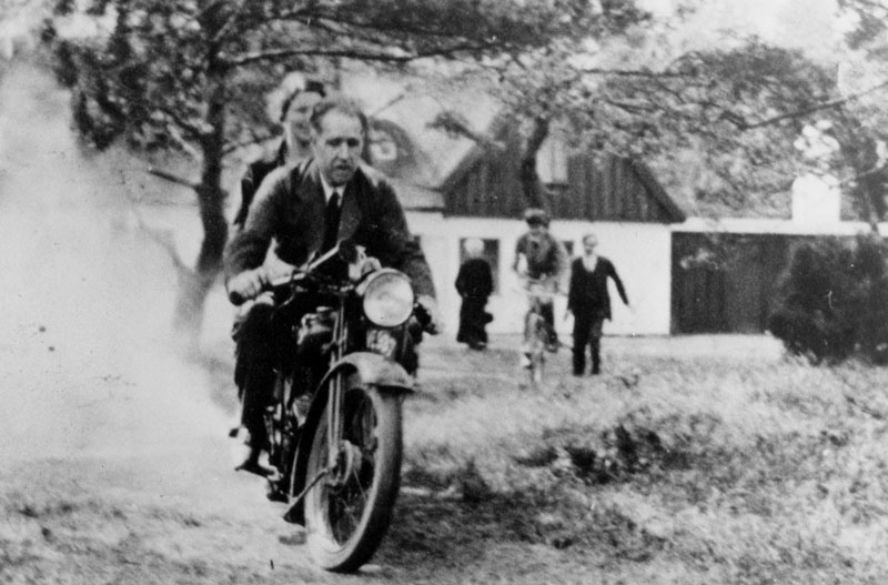 Niels Bohr and his wife Margrethe ride George Gamow’s motorcycle at their summer home in Tisvilde, Denmark. 