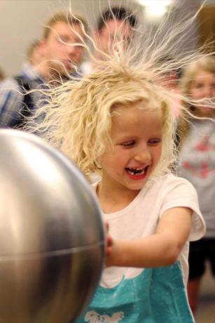 Audience member Payton Martin has a hair-raising experience with a Van de Graaff generator. Photo courtesy of Ben Pound.