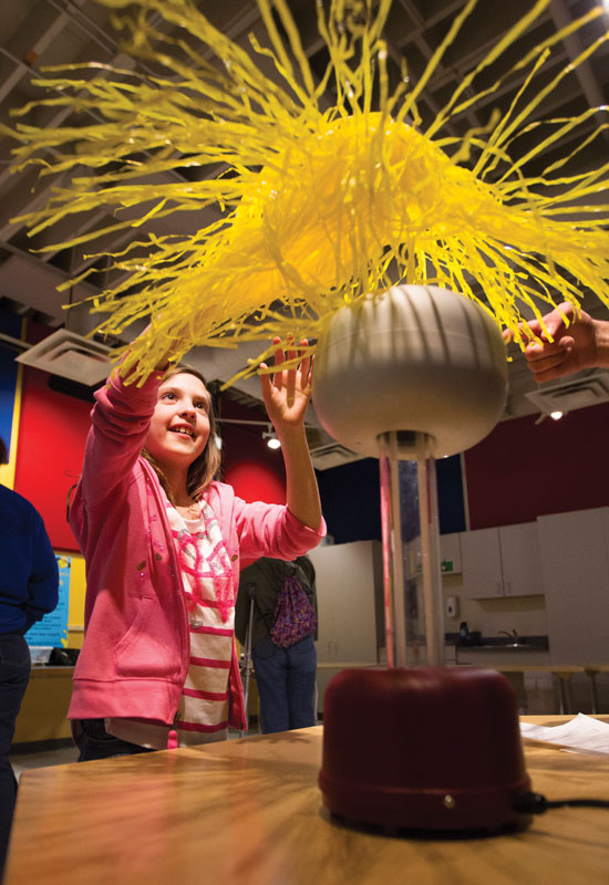A young girl explores the wonder of static electricity with a Van de Graaff generator.