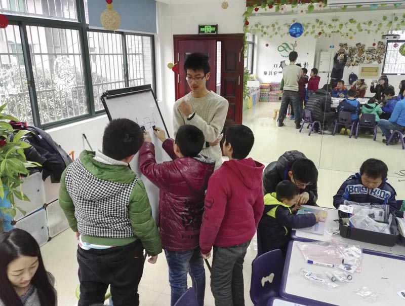 A member of the OSA student chapter at Zhejiang University works with children from Youth Homes in Hangzhou on activities from the Optics Suitcase. Photo courtesy of The Optical Society.