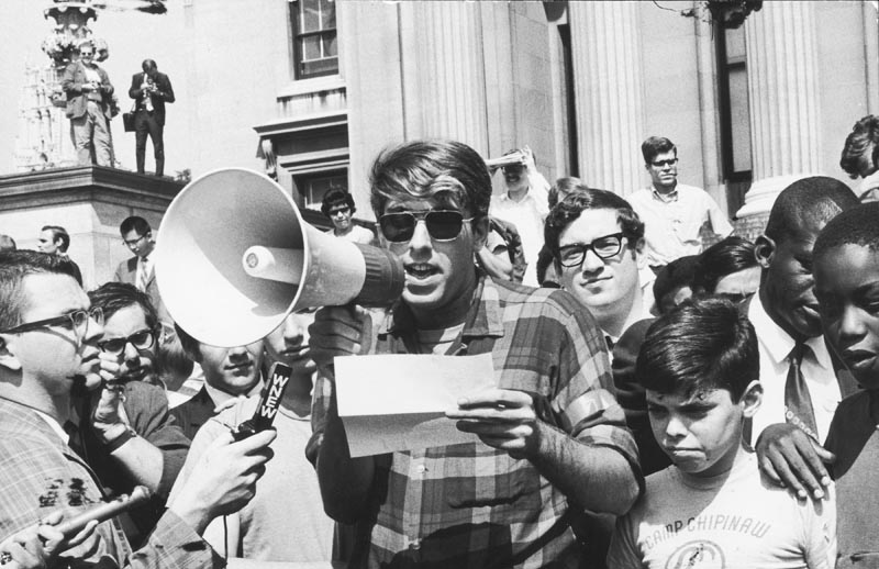 During the height of the 1968 protests at Columbia University, American political activist Mark Rudd, a leader of Students for a Democratic Society (SDS), reads the organization's 'Student Demands to School Administration' through a bullhorn to assembled students and journalists, New York, New York, September 20, 1968. Photo by Fred W. McDarrah/Getty Images.