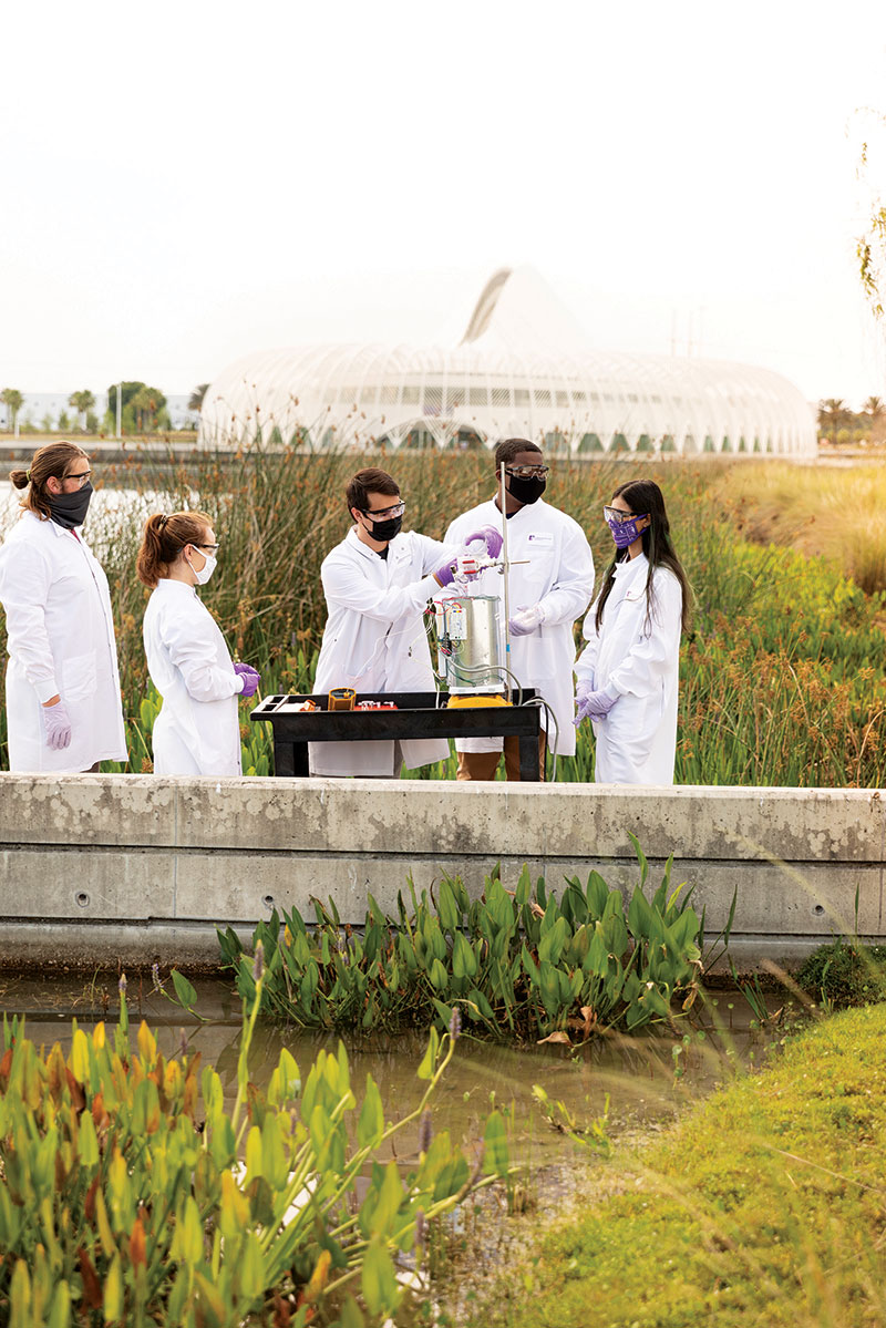 SPS members and a local middle school student set up a batch reactor near FL Poly’s pond to treat wastewater. In the background is the campus’ state-of-the-art Innovation, Science, and Technology Building, surrounded by pond water. 