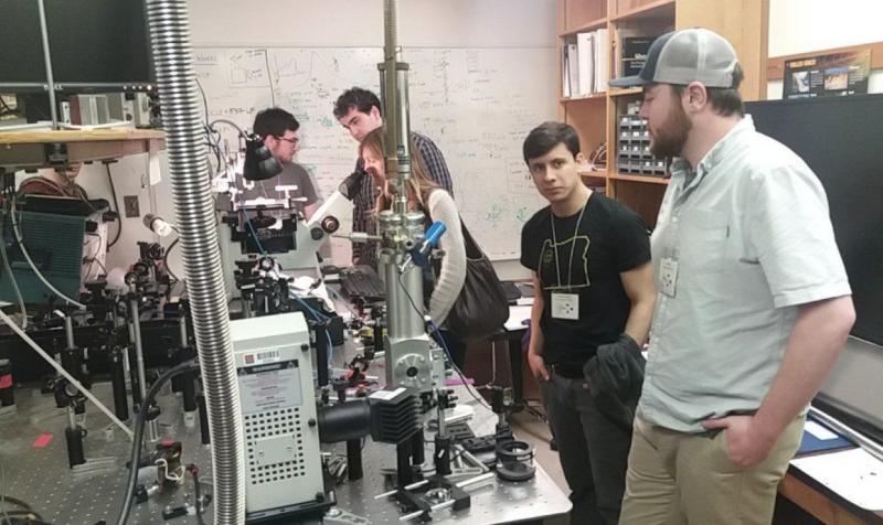 A group of attendees touring Nicole Quist’s optics lab.