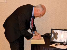 AIP CEO Robert G.W. Brown signing the &quot;Red Book&quot; after being inducted into Sigma Pi Sigma. Photo by Matt Payne.
